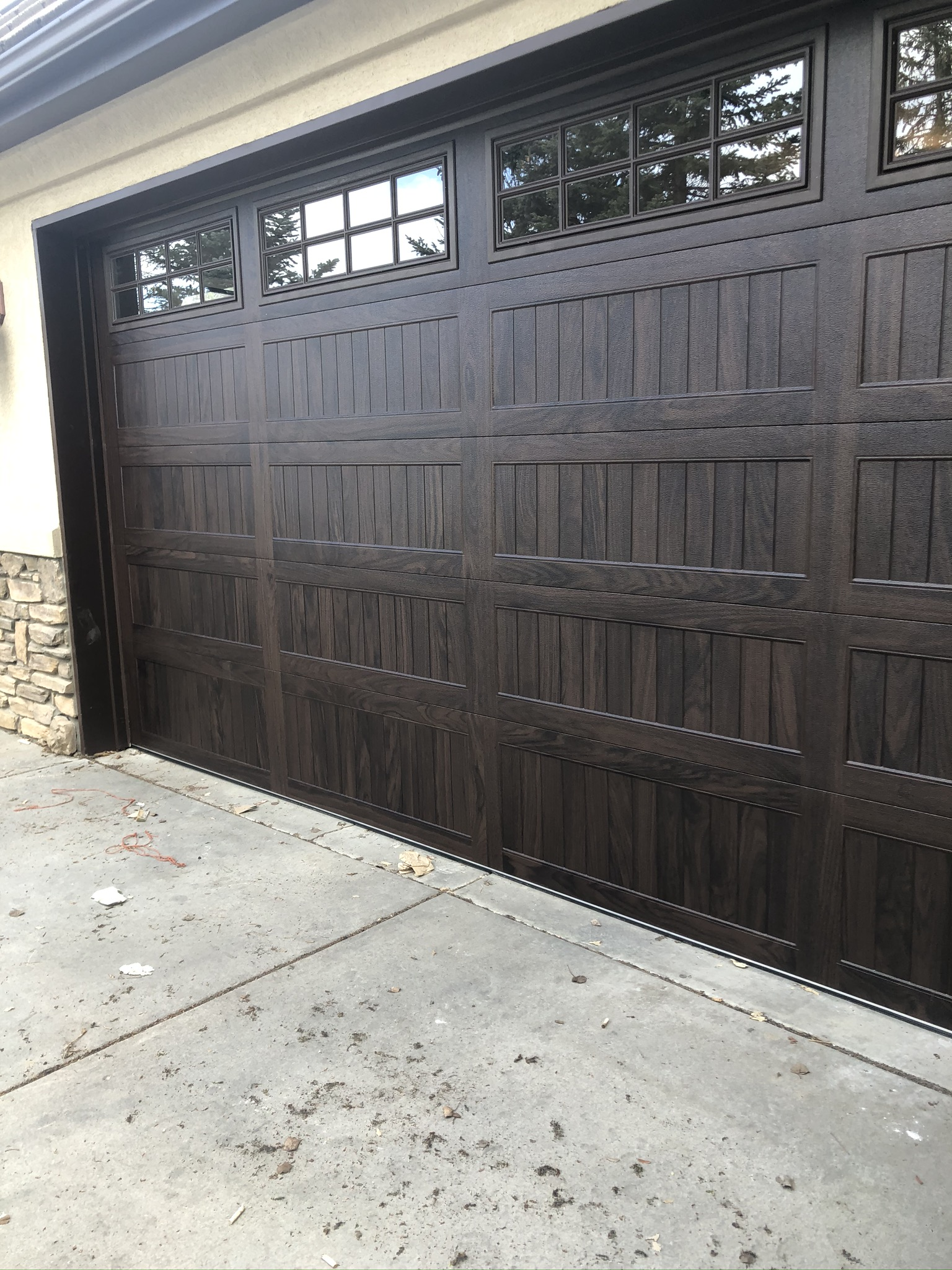 A brown garage door with a lot of windows is sitting on a concrete driveway.