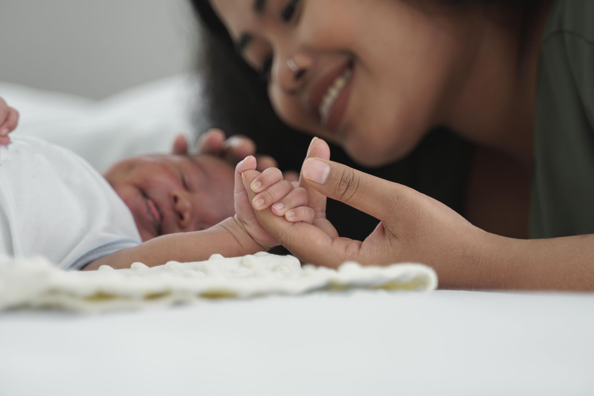 Nurse gently examines a newborn on a changing table in a bright clinic room