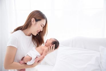 Woman smiling at a baby in a bright white bedroom
