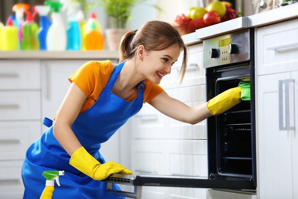 Woman Cleaning a Kitchen Oven Woman Cleaning a Kitchen Oven