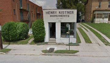 Henry Kistner Monuments storefront with green shrubs and sidewalk frontage