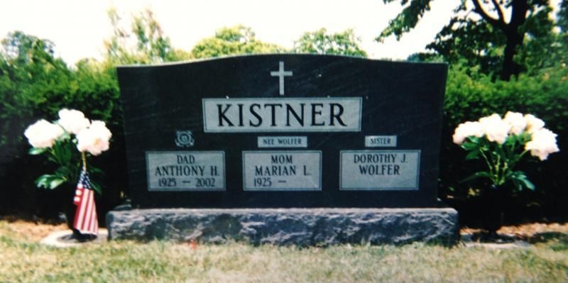 Kistner family gravestone with white flowers and small American flag in a cemetery