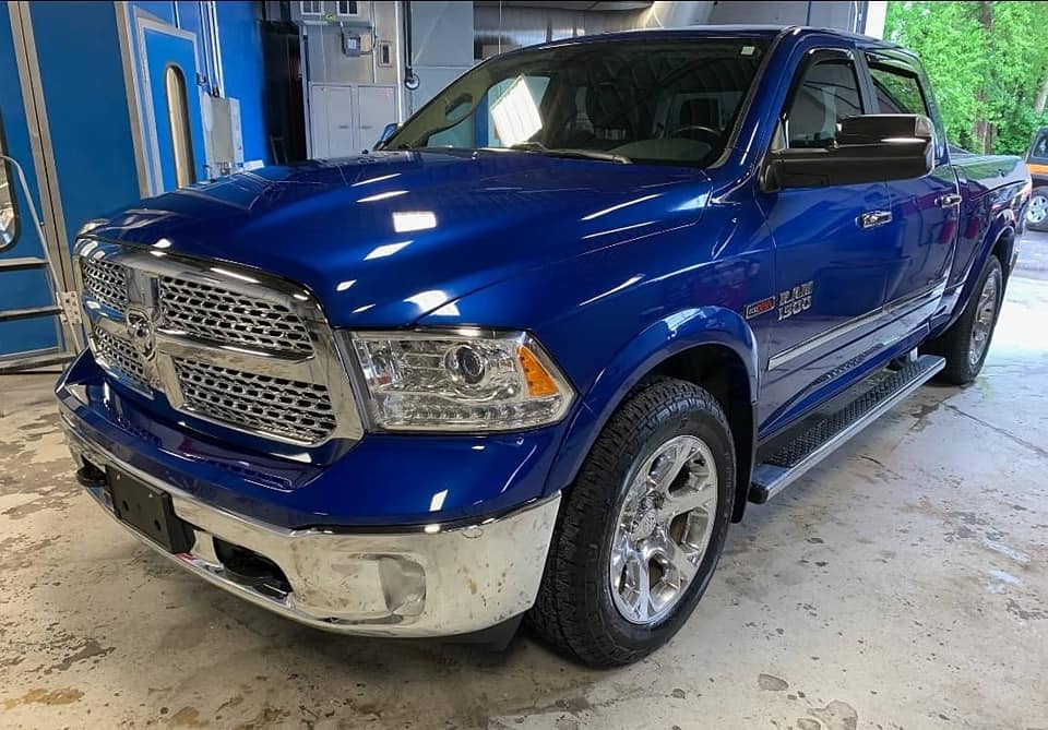 A blue dodge ram truck is parked in a garage.