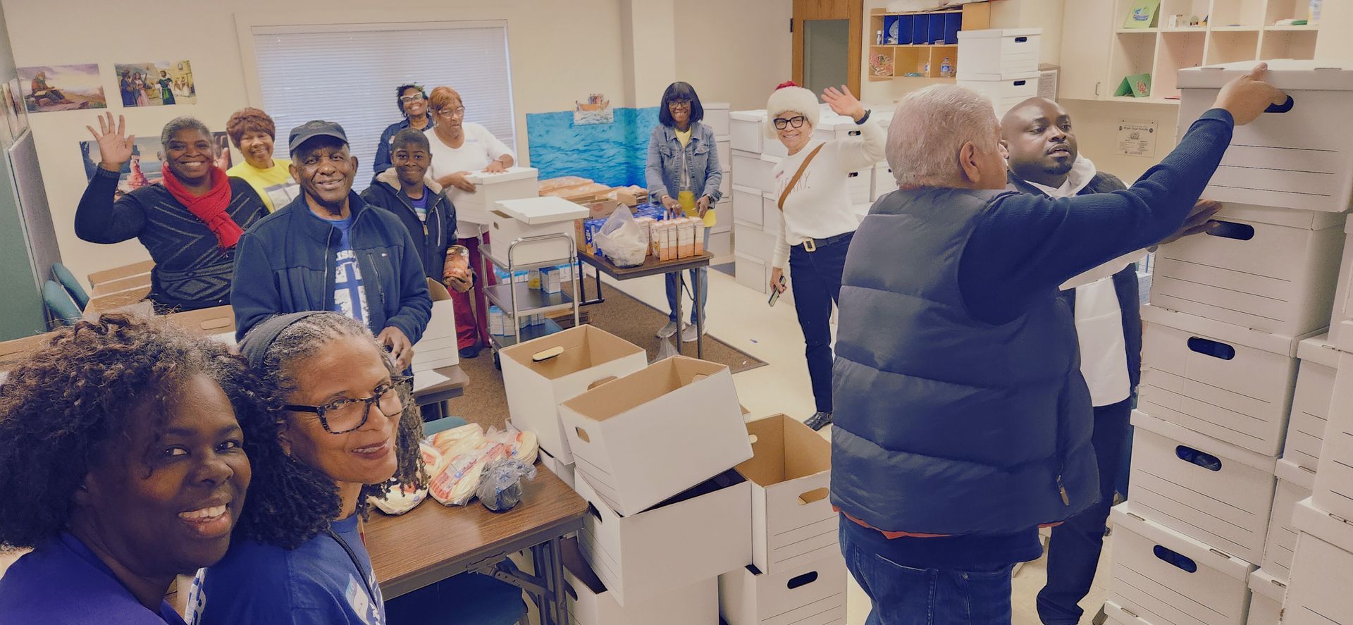 A group of volunteers in a storage room packing and organizing white cardboard boxes.