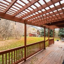 House porch with central stairs and wheelchair ramp, with handrails and wooden walkway in a wooded yard.