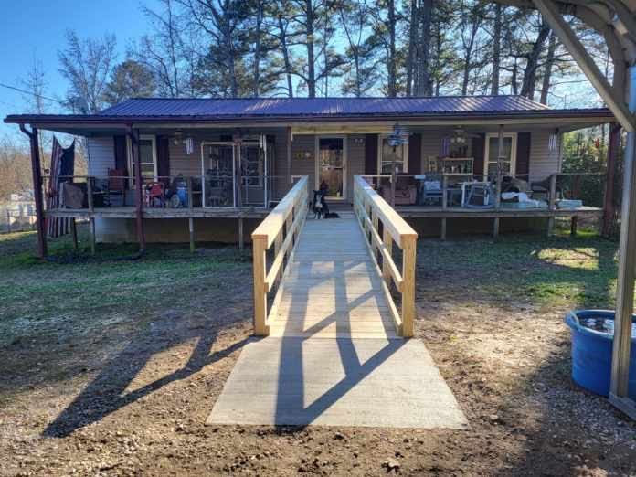 Front porch ramp leading to a single-story house with a blue roof and covered porch.