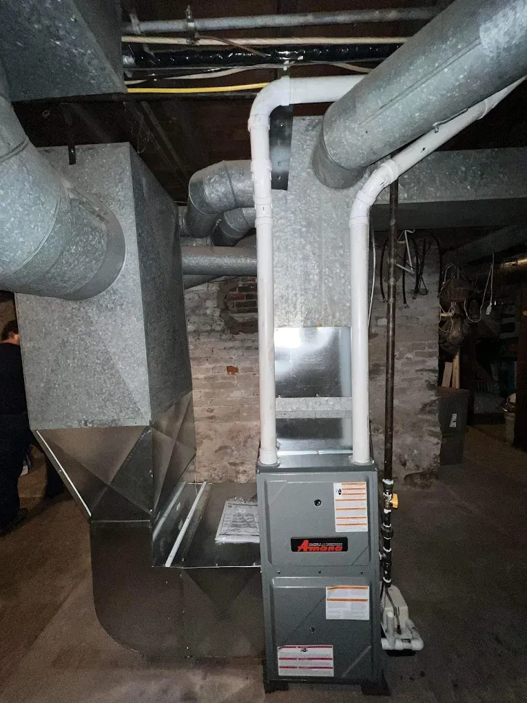 A furnace system in a basement with metallic ductwork.