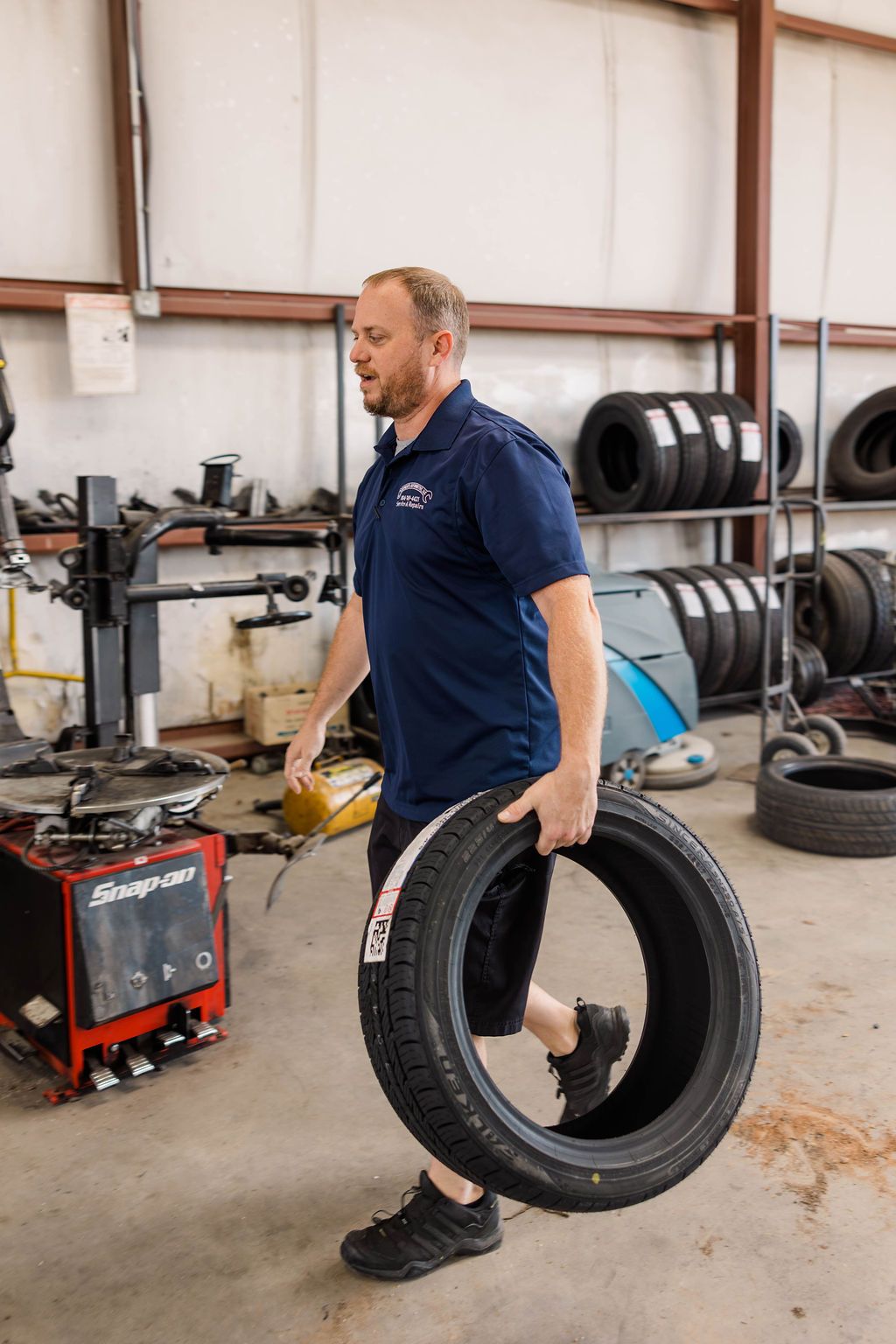 Mechanic carries a tire | Stephen's Automotive