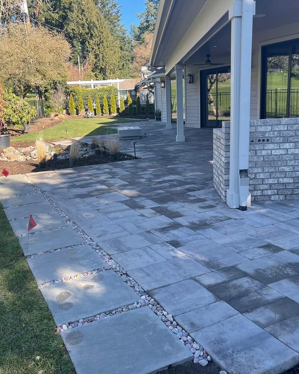 Patio with gray pavers, gravel accents, and a view of a grassy backyard.