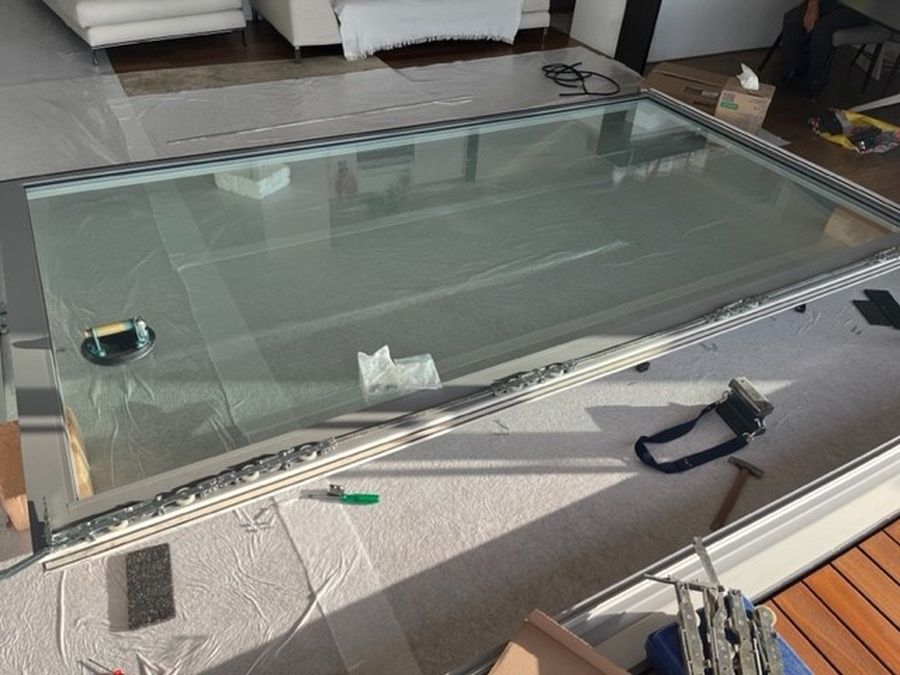 In einem Wohnzimmer wird ein grosser Glastisch aufgestellt.