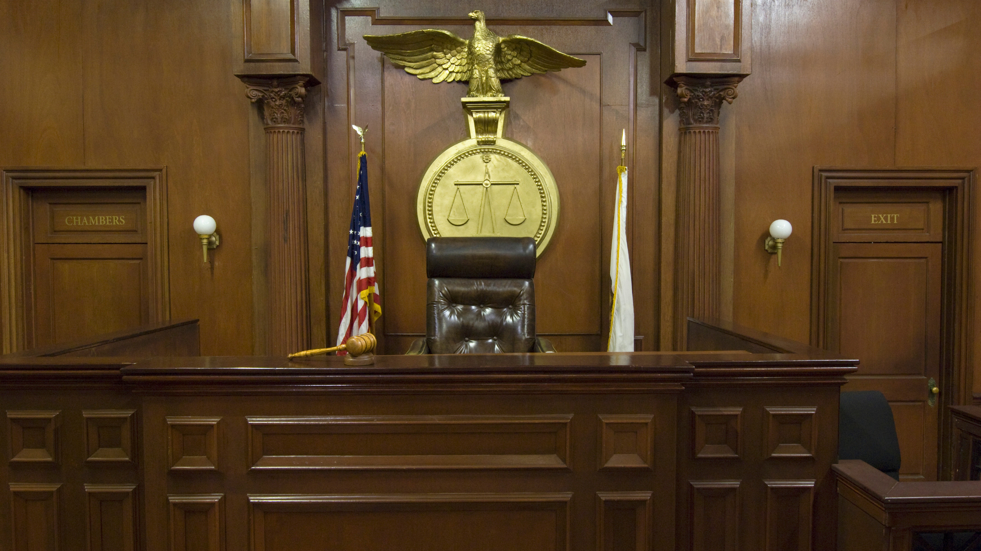 An empty courtroom with a statue of an eagle on the judge 's bench.