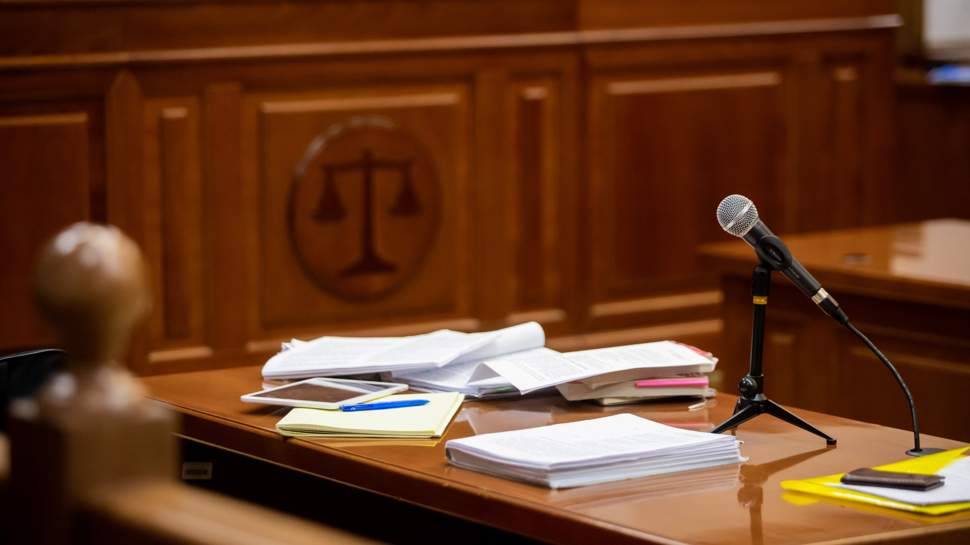 A microphone is sitting on a wooden table in a courtroom.