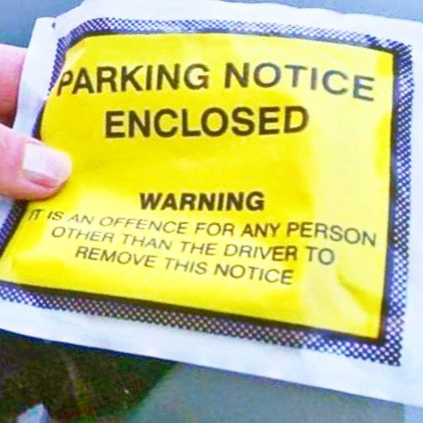 Yellow parking notice warning about removal, held by a hand.