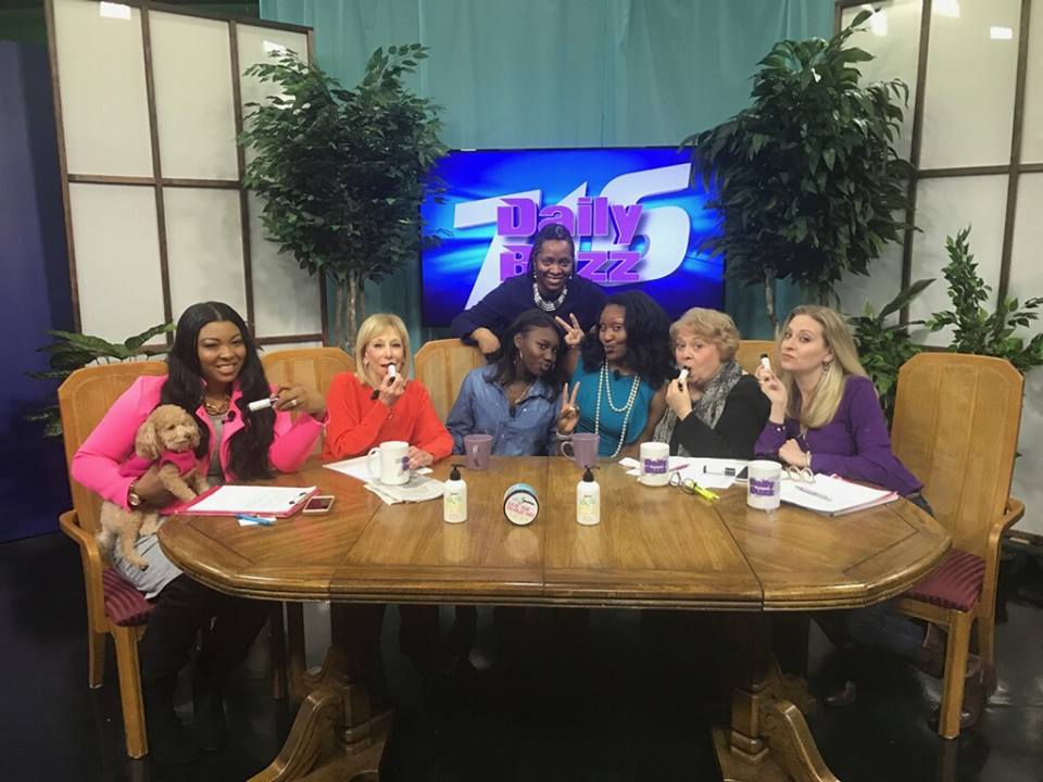 A group of women are sitting around a table in front of a tv with the number 75 on it