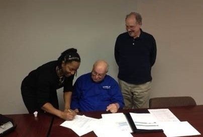 Two men and a woman are sitting at a table with papers on it