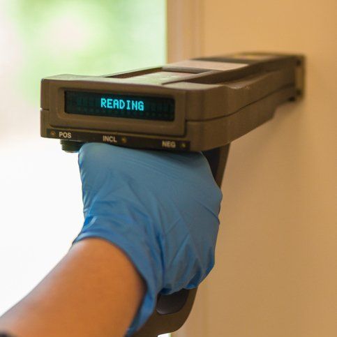 A person wearing blue gloves is holding a device that says reading