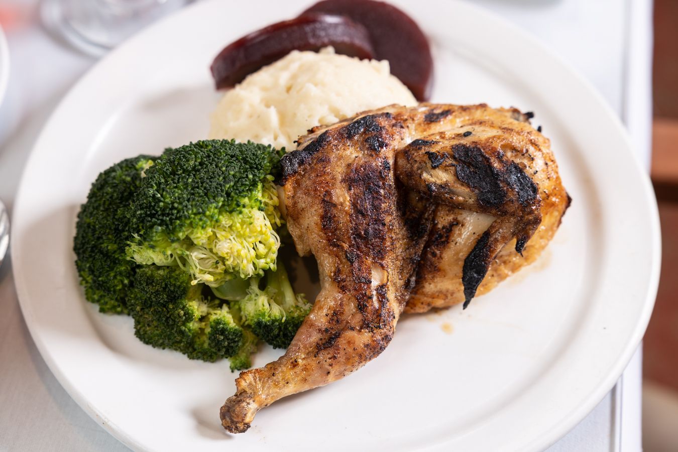 A white plate topped with chicken , broccoli and mashed potatoes.