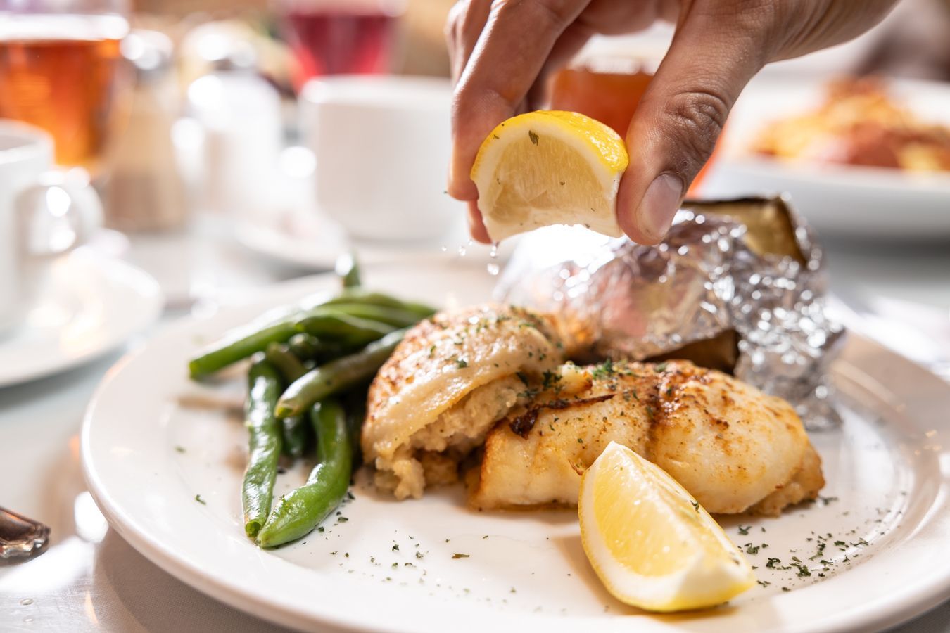 A person is squeezing a lemon over a plate of food.