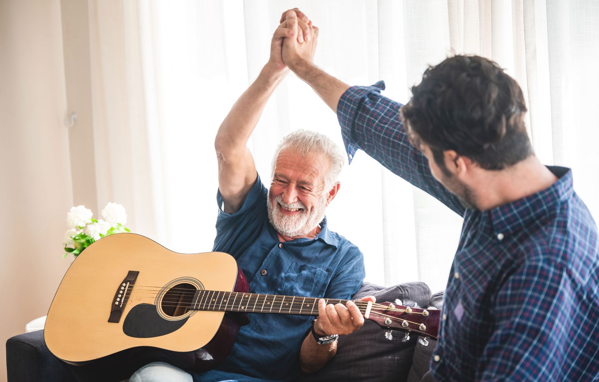 Two men are giving each other a high five while playing a guitar.