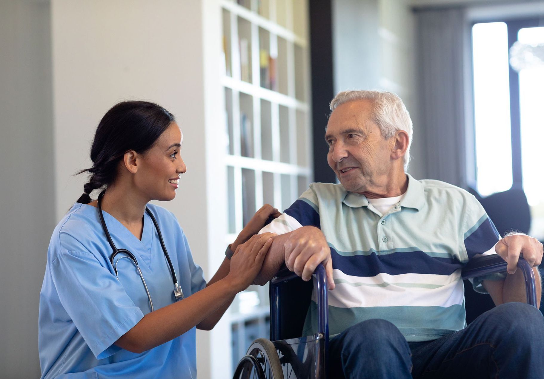 A woman is holding a laptop next to an senior man on an exercise bike