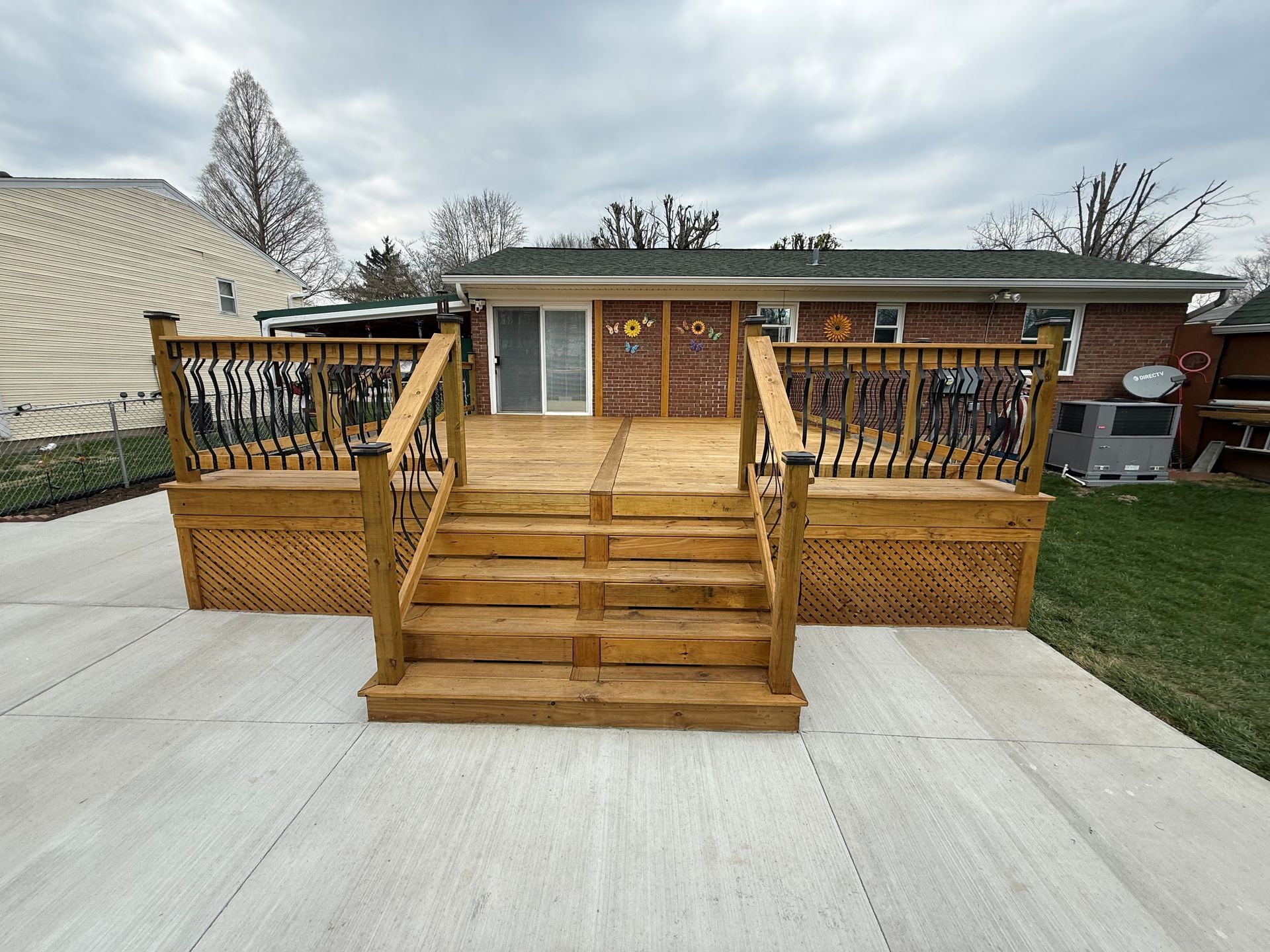 Screened-in porch with wood benches, string lights, and a wooden deck overlooking a wooded area.