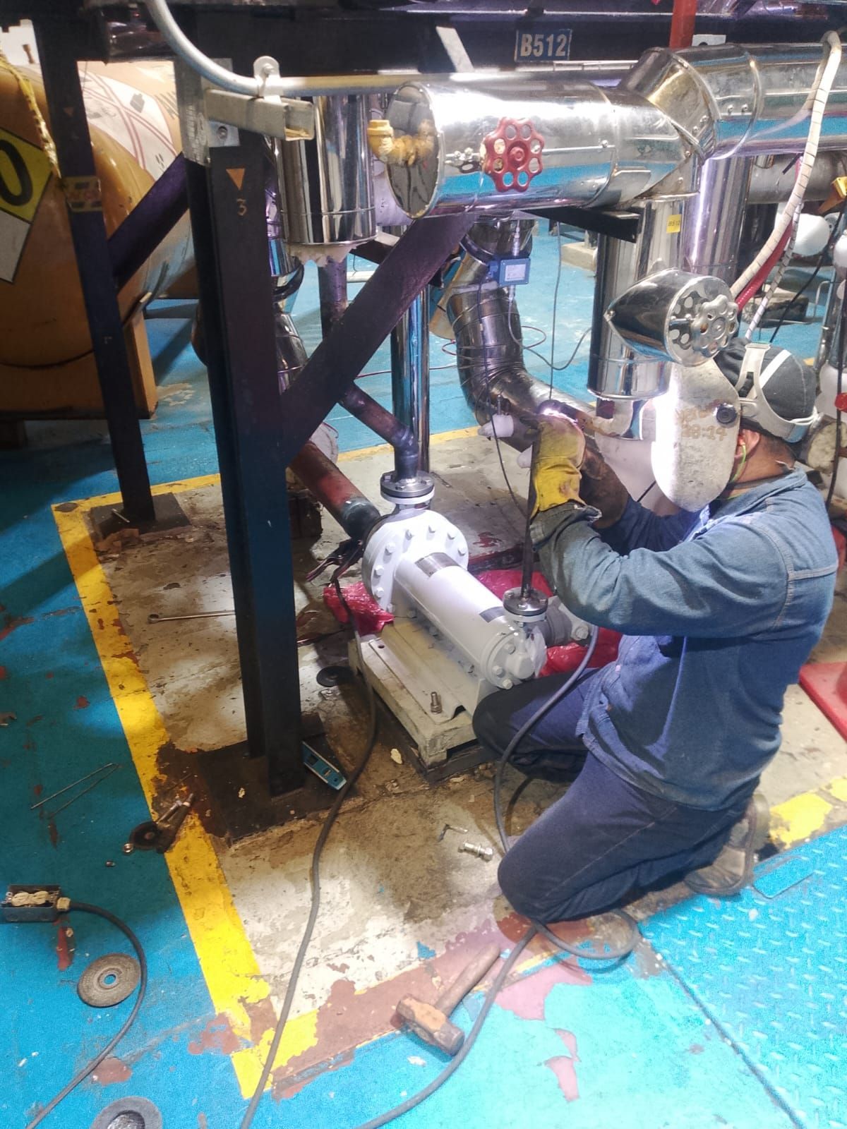 Un trabajador se arrodilla junto a una tubería industrial