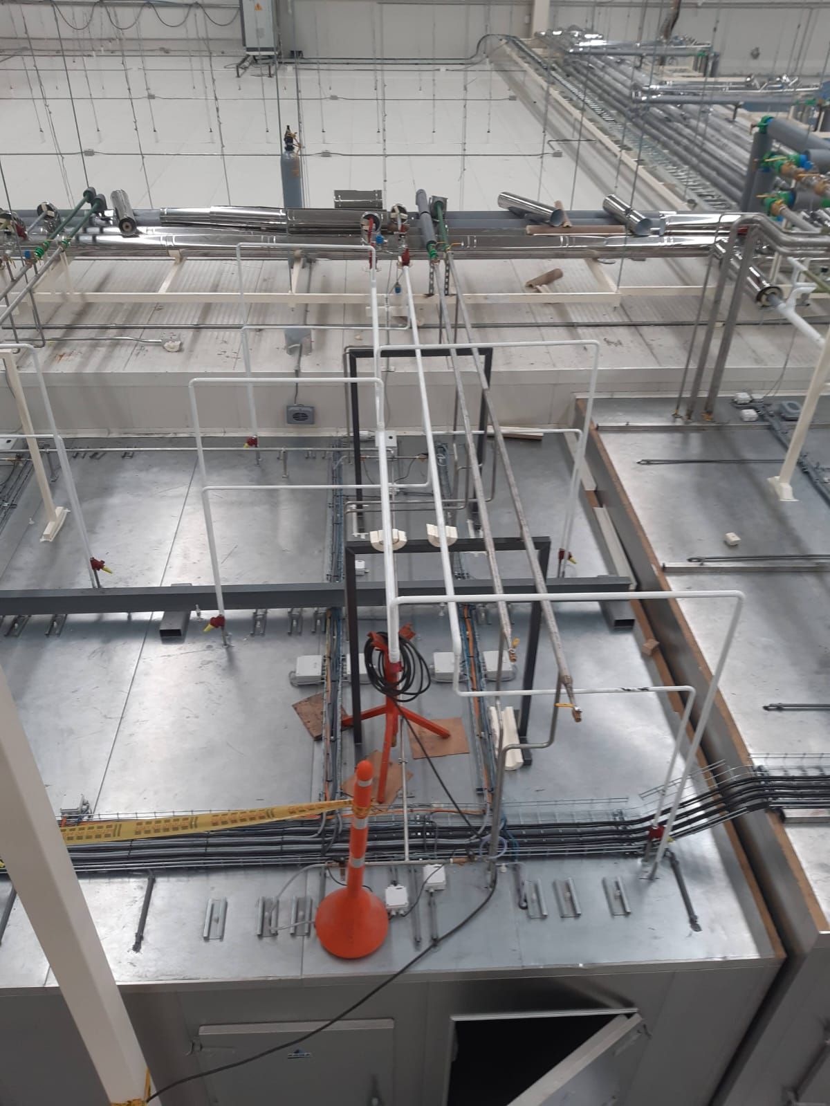 Máquina industrial con rieles metálicos, herramienta de ventosa naranja y cableado en un espacio de trabajo de fábrica.
