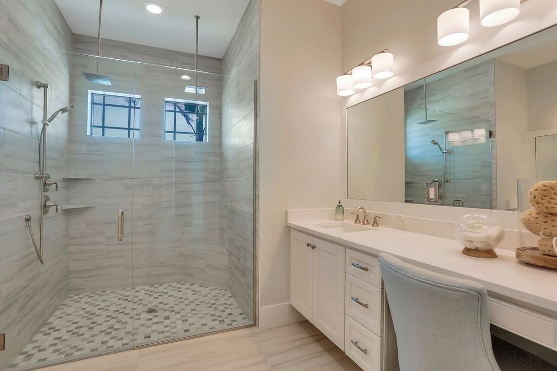 Bright modern bathroom with walk-in glass shower, double vanity, and light tile flooring