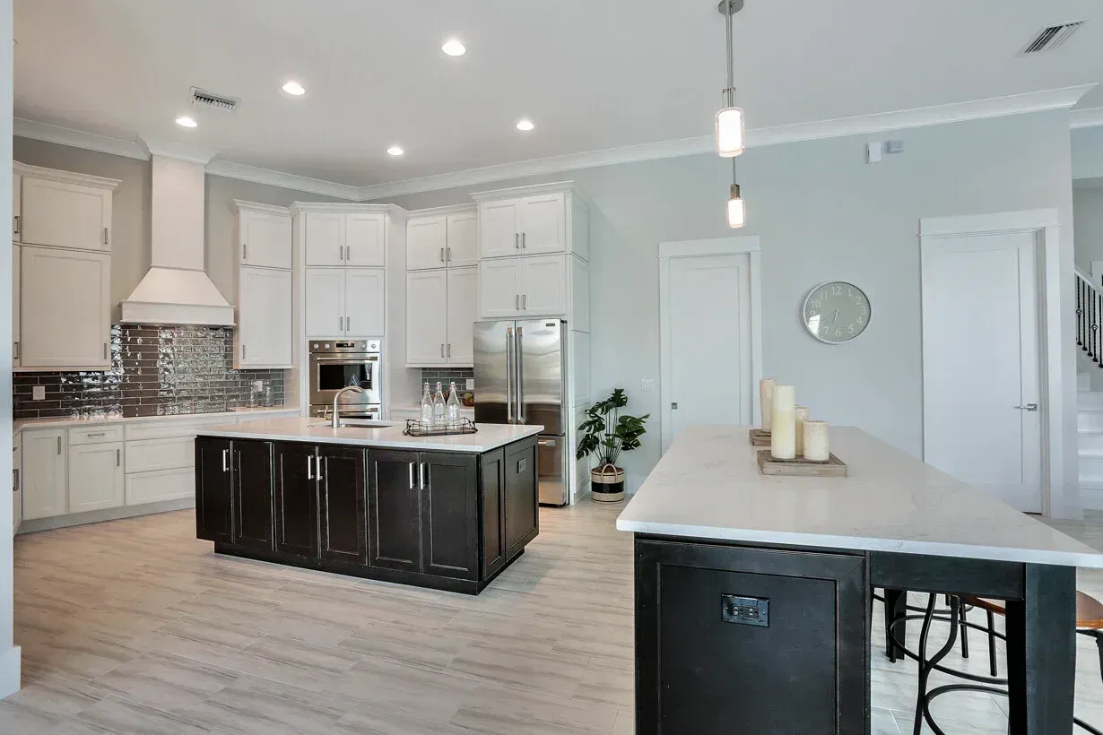 Bright modern kitchen with white cabinets, dark island, stainless appliances, and light wood floors