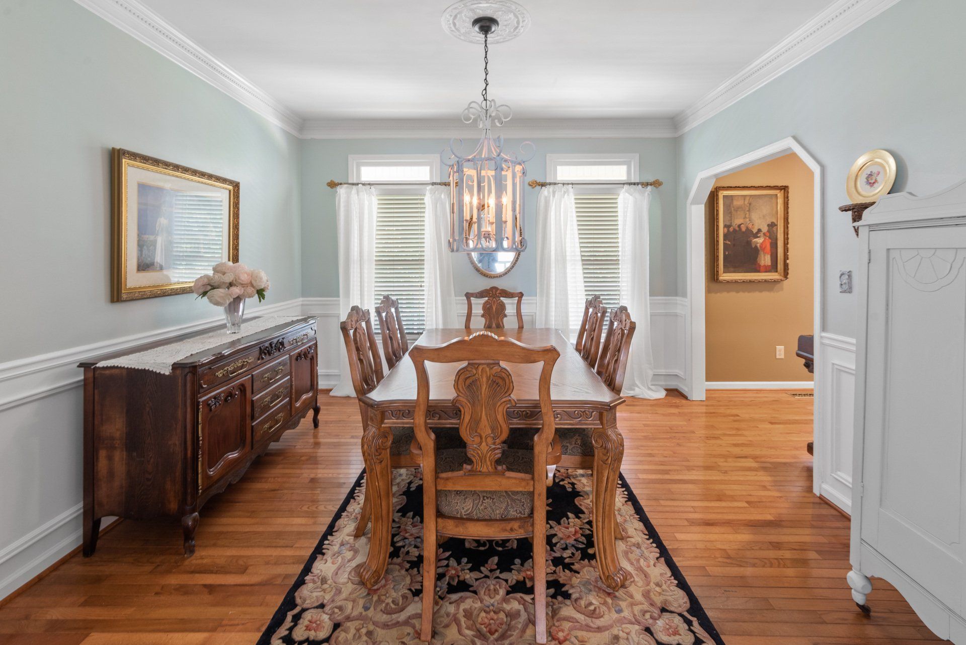 Formal dining room with wood table, chairs, buffet, and chandelier.