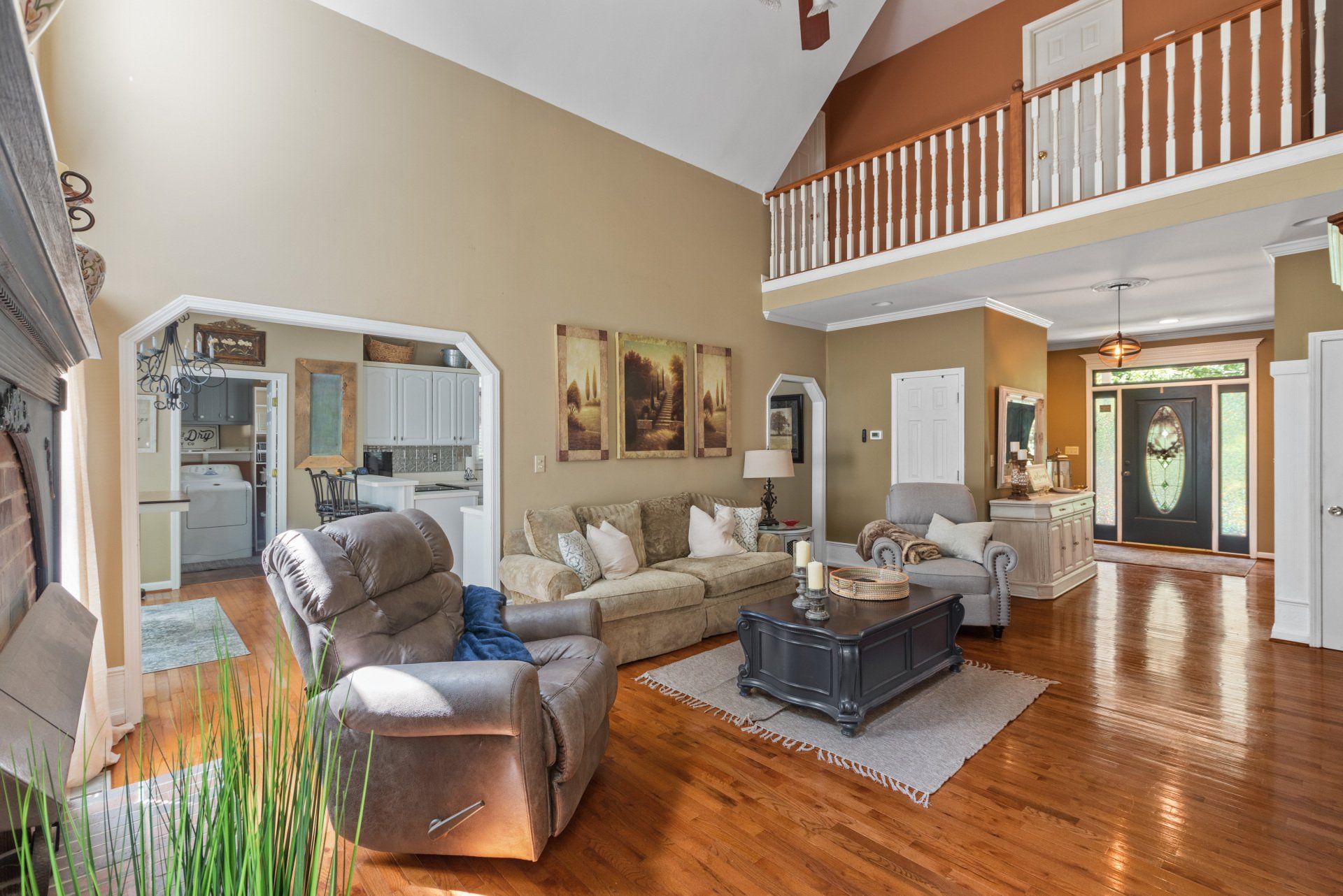 Spacious living room with hardwood floors, a loft, and an open entryway to the kitchen.