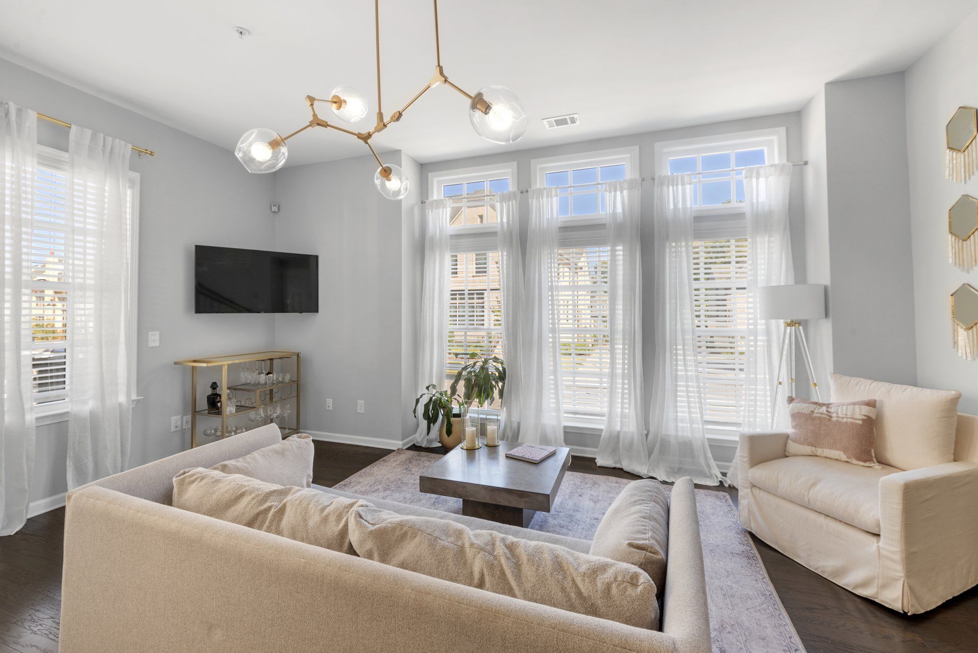 Living room of a condo with a nice couch, tv, and lots of natural light