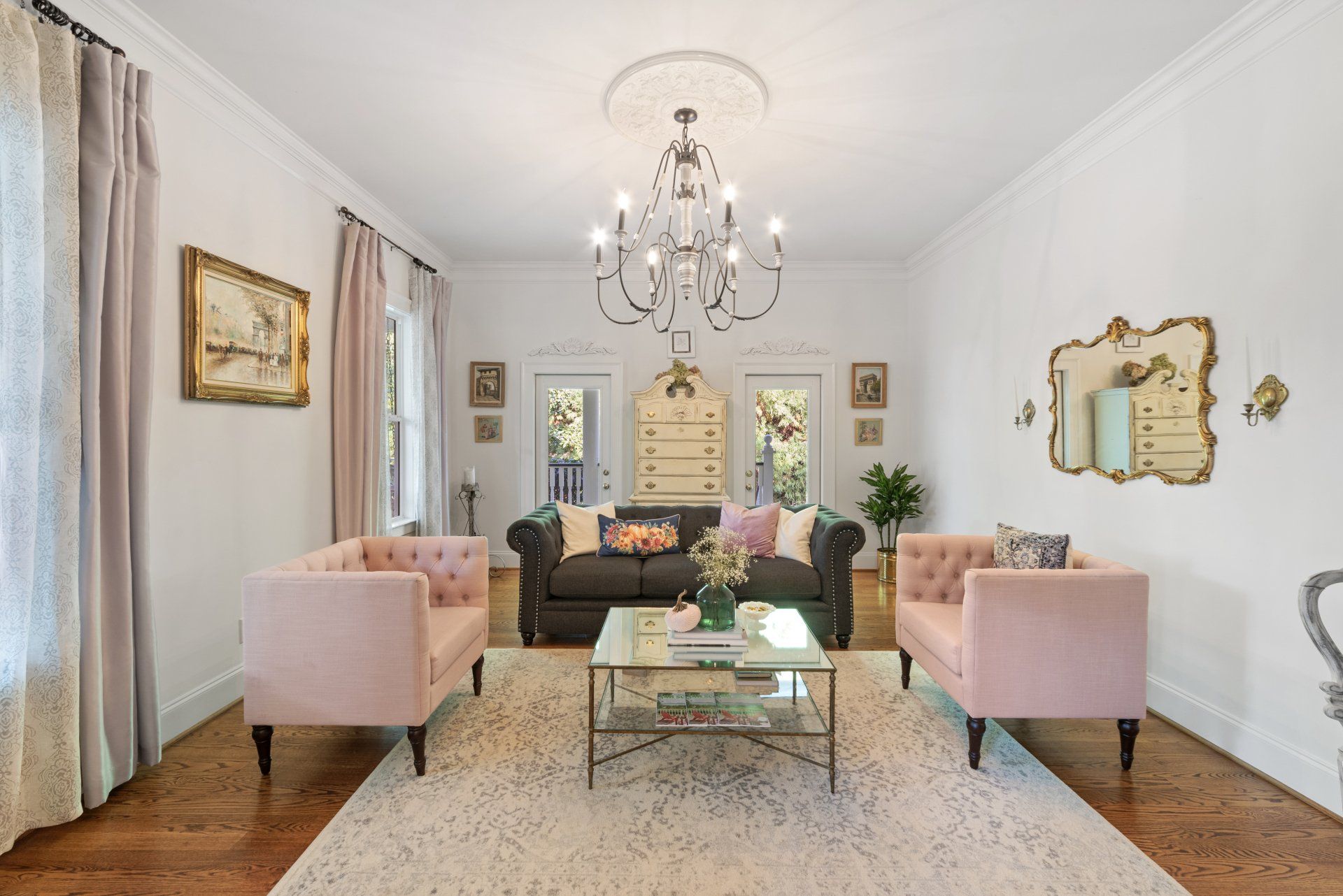 Living room with pink and dark gray furniture, chandelier, and a white rug.
