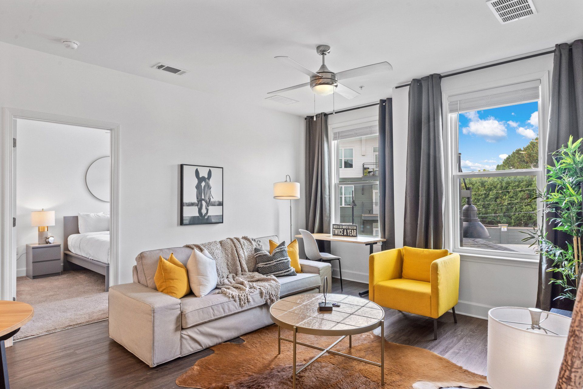 Living room with couch, yellow chair, coffee table, and open window.