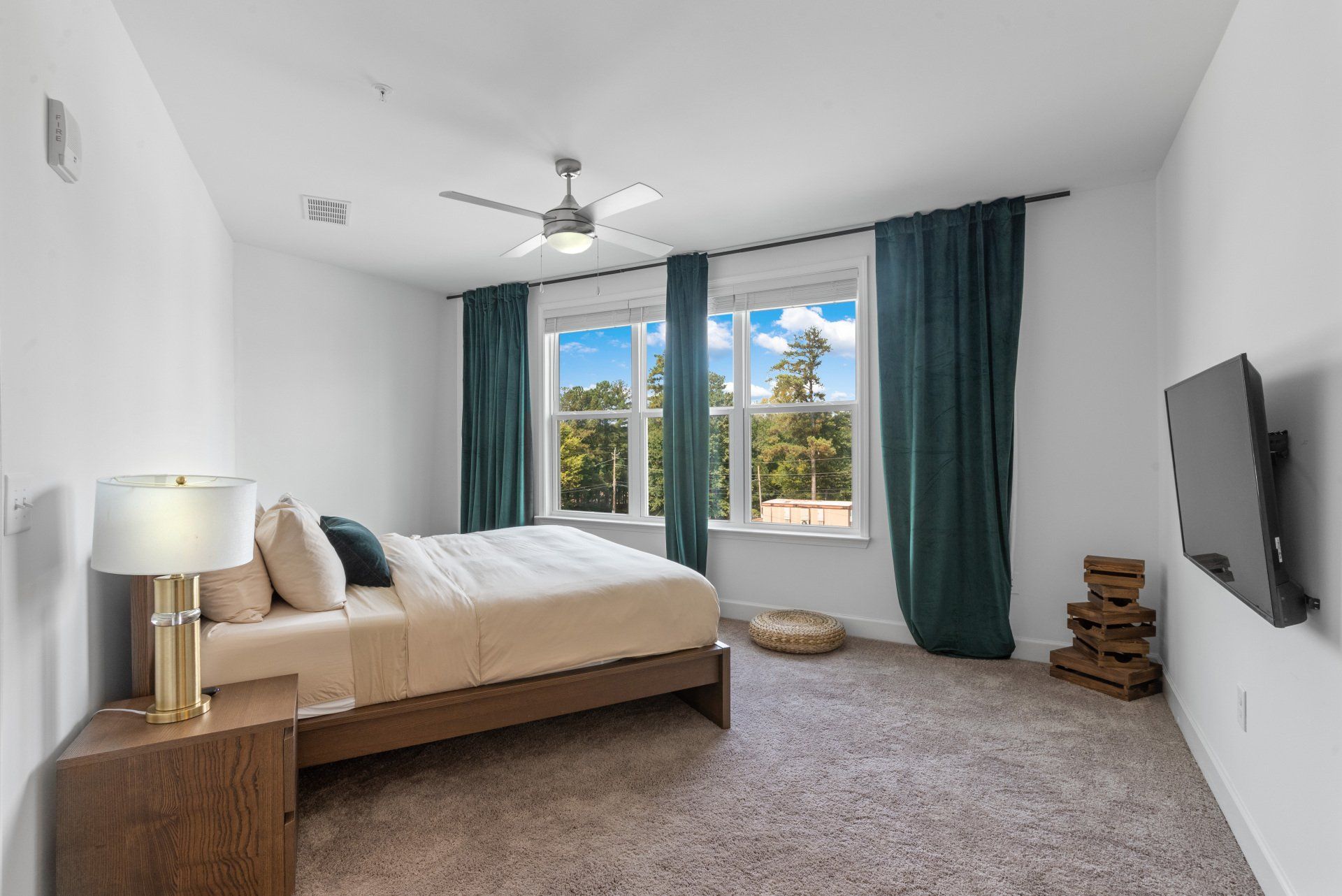 Bedroom with bed, nightstand, window, TV, and teal curtains.