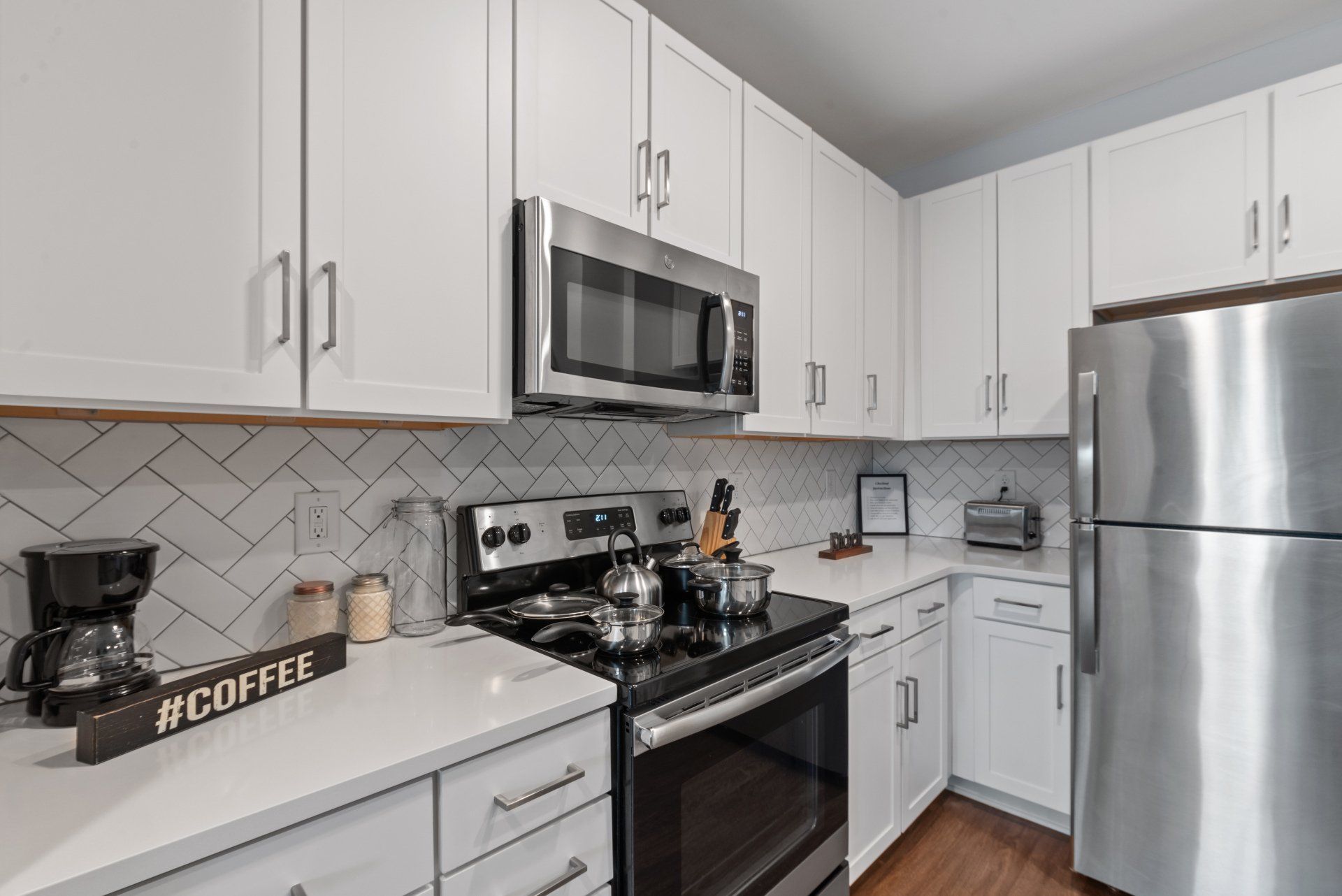 White kitchen with stainless steel appliances, white cabinets, and backsplash.