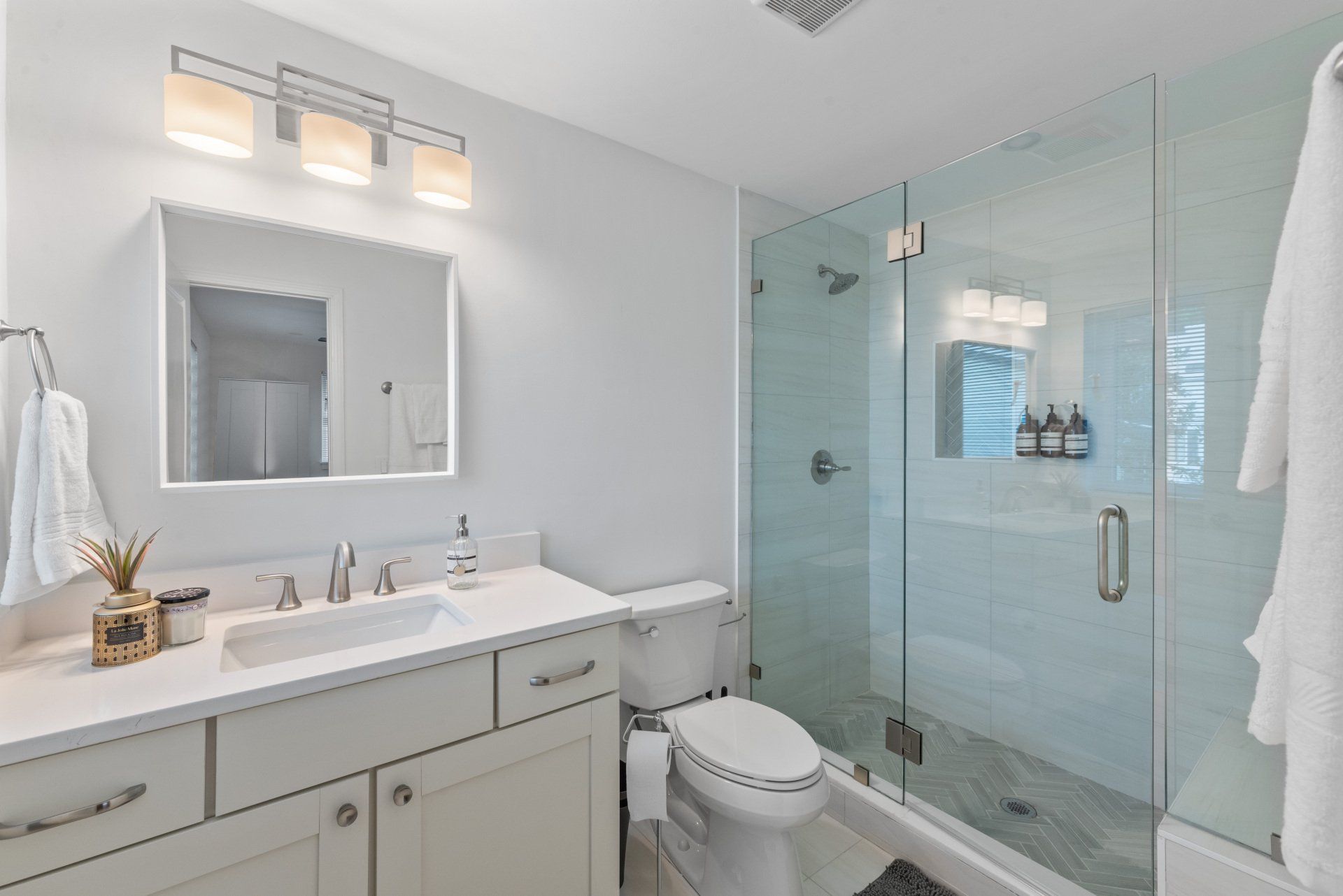 White bathroom with glass shower, toilet, and vanity.