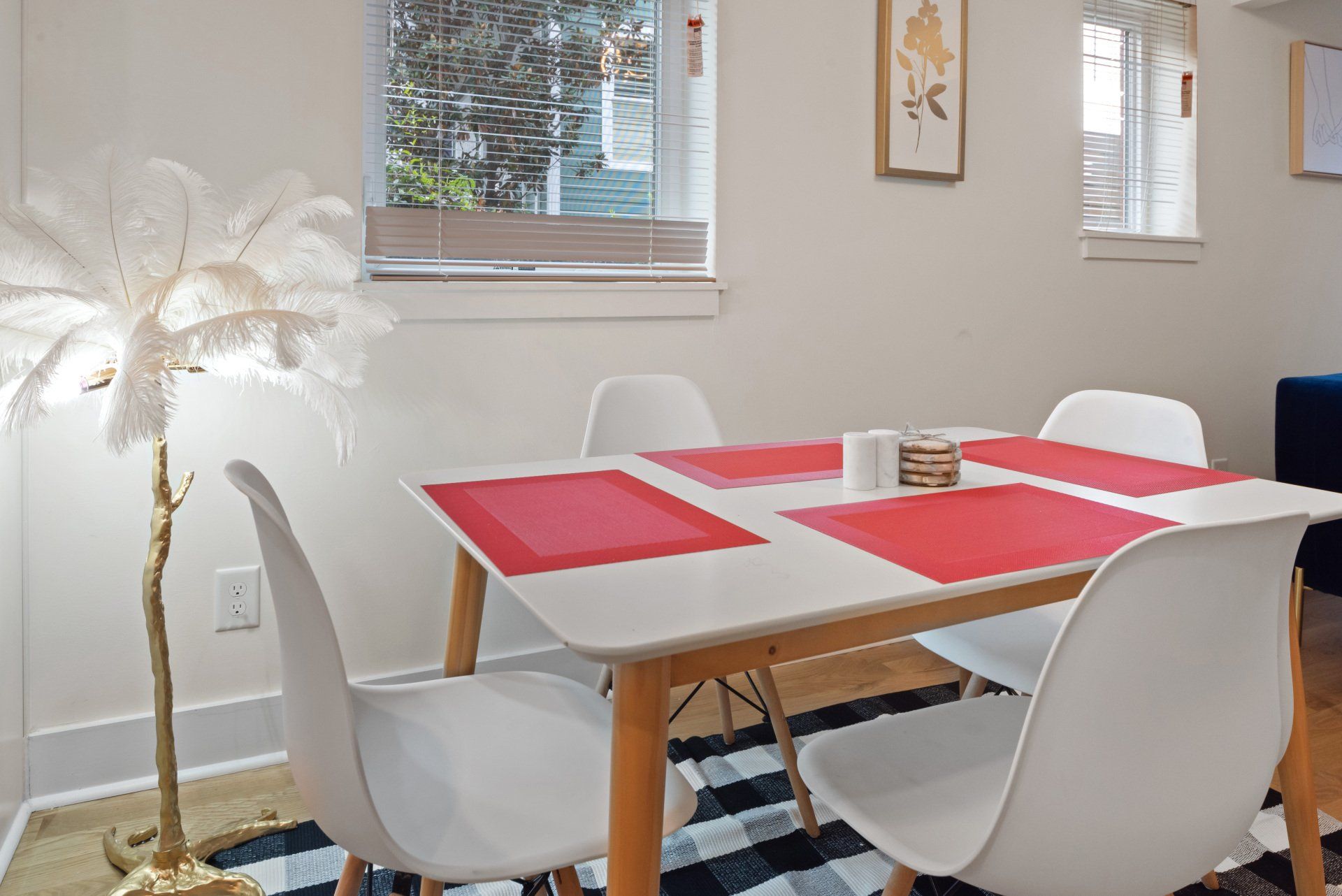 Dining area with a white table, chairs, and a decorative feather floor lamp.