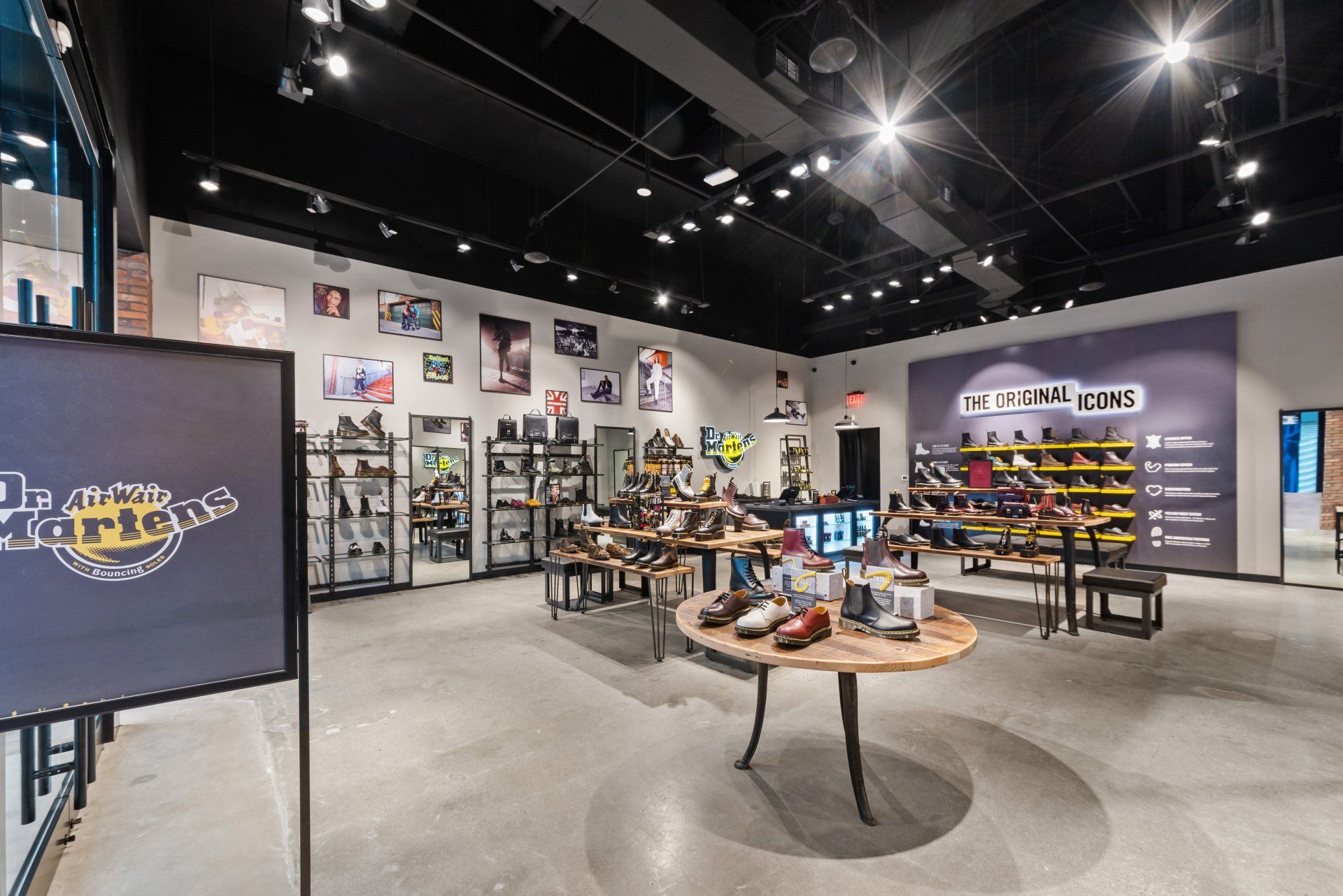 Interior of a Dr. Martens store with shoe displays and seating. White walls, black ceiling, and gray floors.