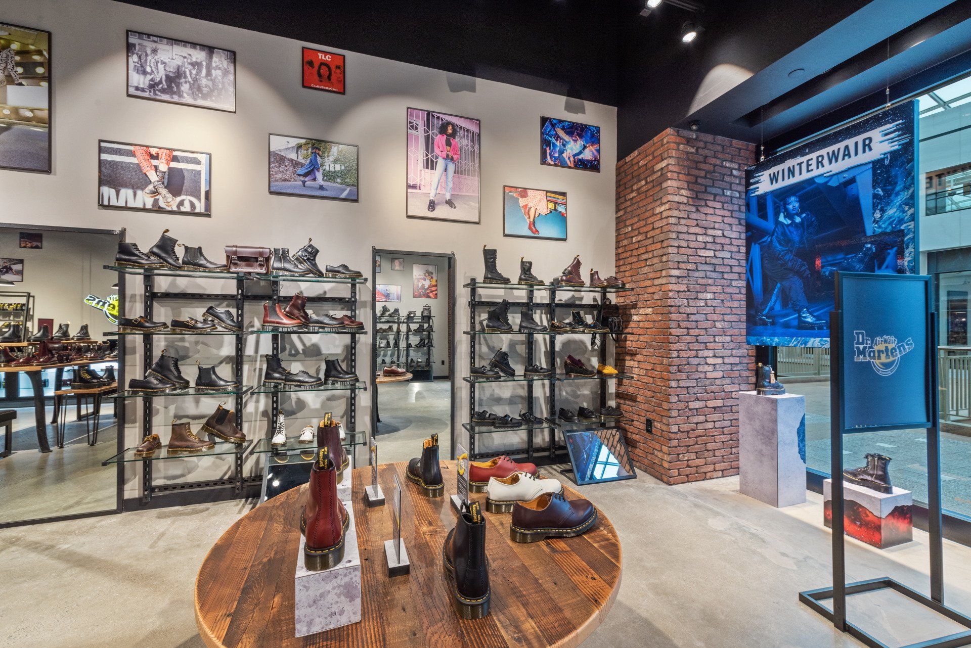 Inside a Dr. Martens shoe store, displays of boots surround an oval table and line the walls.