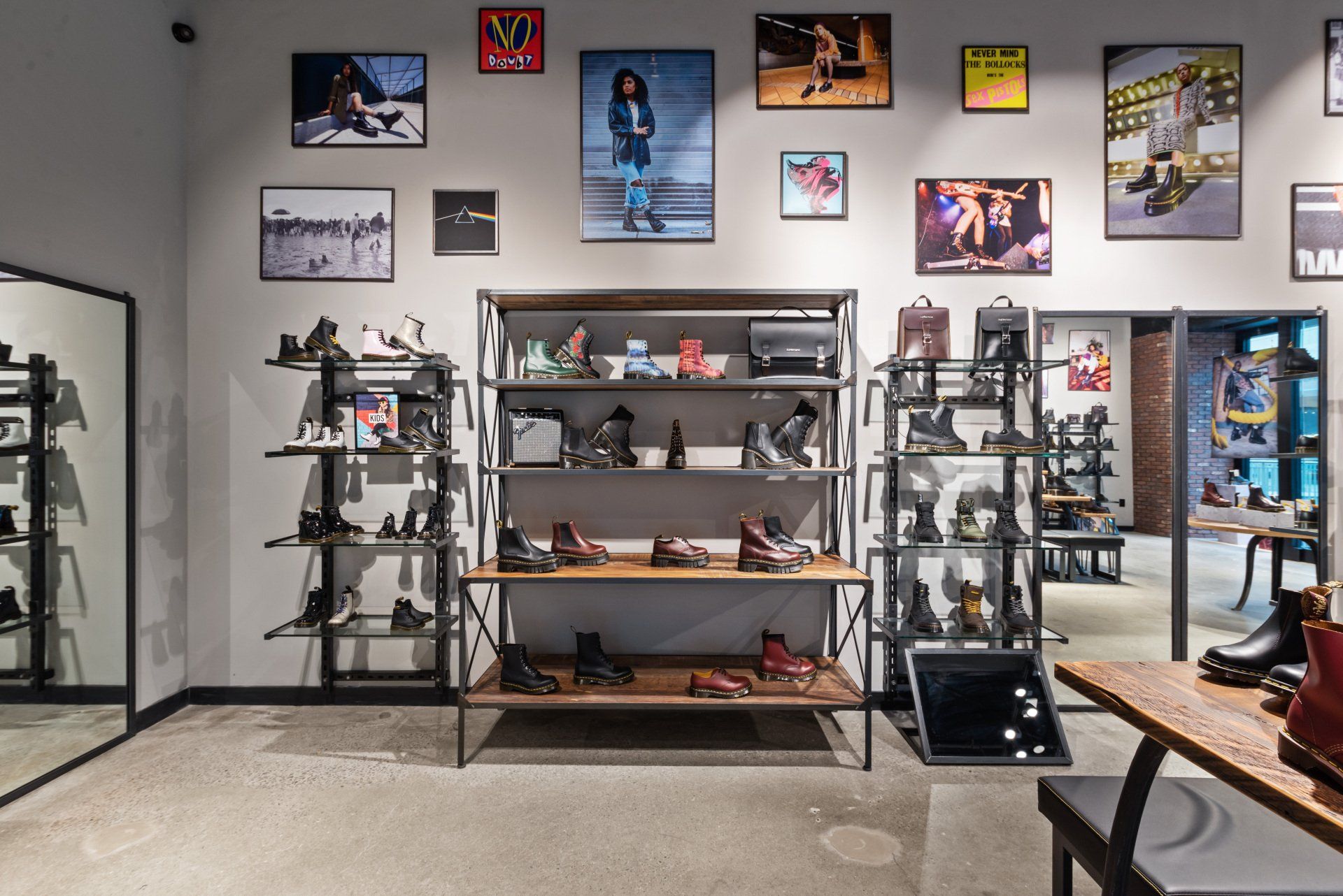 Inside a shoe store, shelves display boots and accessories, with posters on the wall.