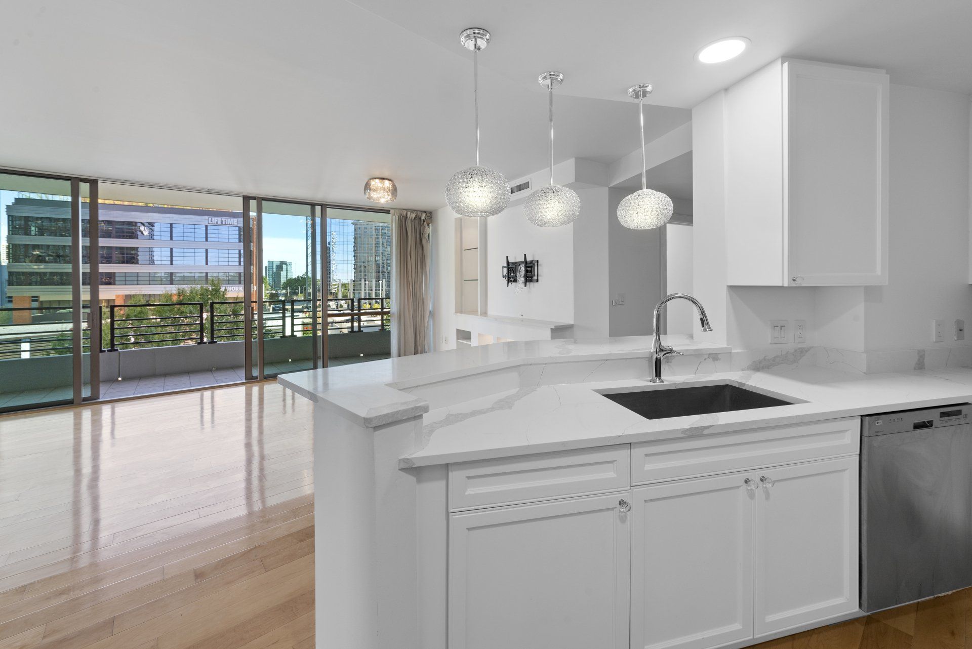 Modern kitchen with white cabinets, stainless steel appliances, and a balcony view.