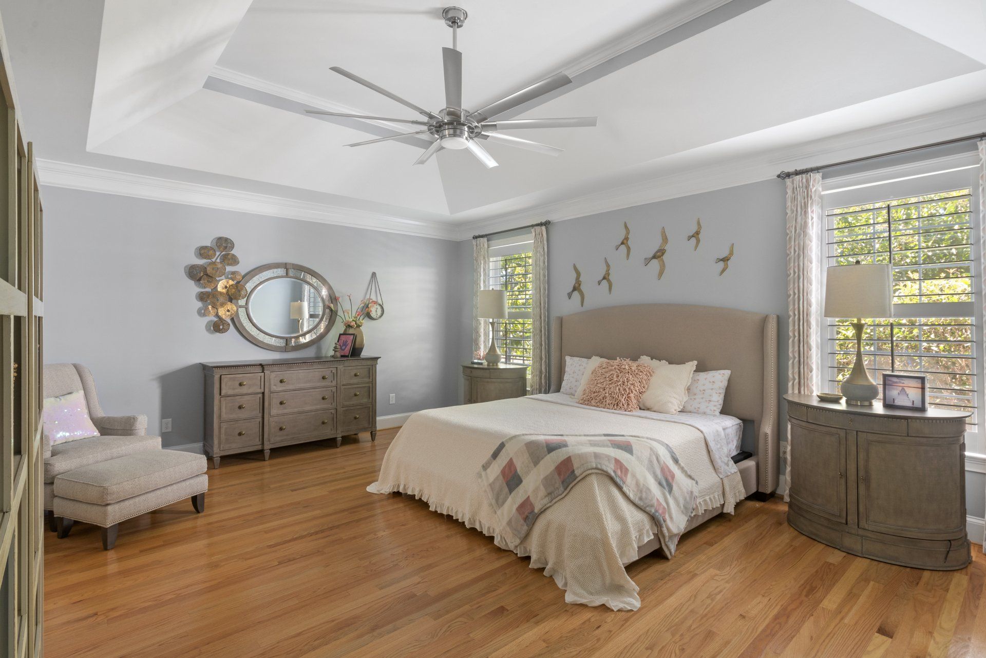 Bedroom with hardwood floors, light blue walls, and a large bed with a headboard.