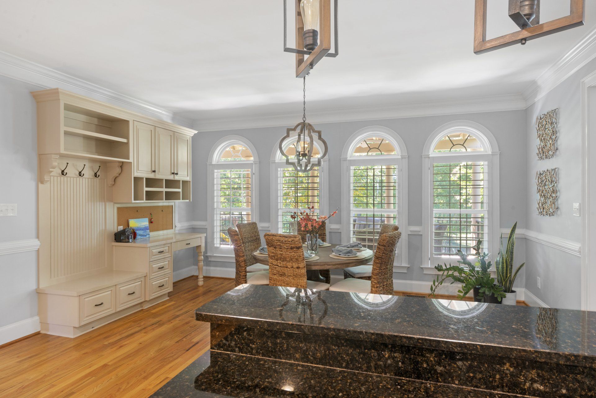 Dining room with arched windows, round table, and a kitchen island with a granite countertop.