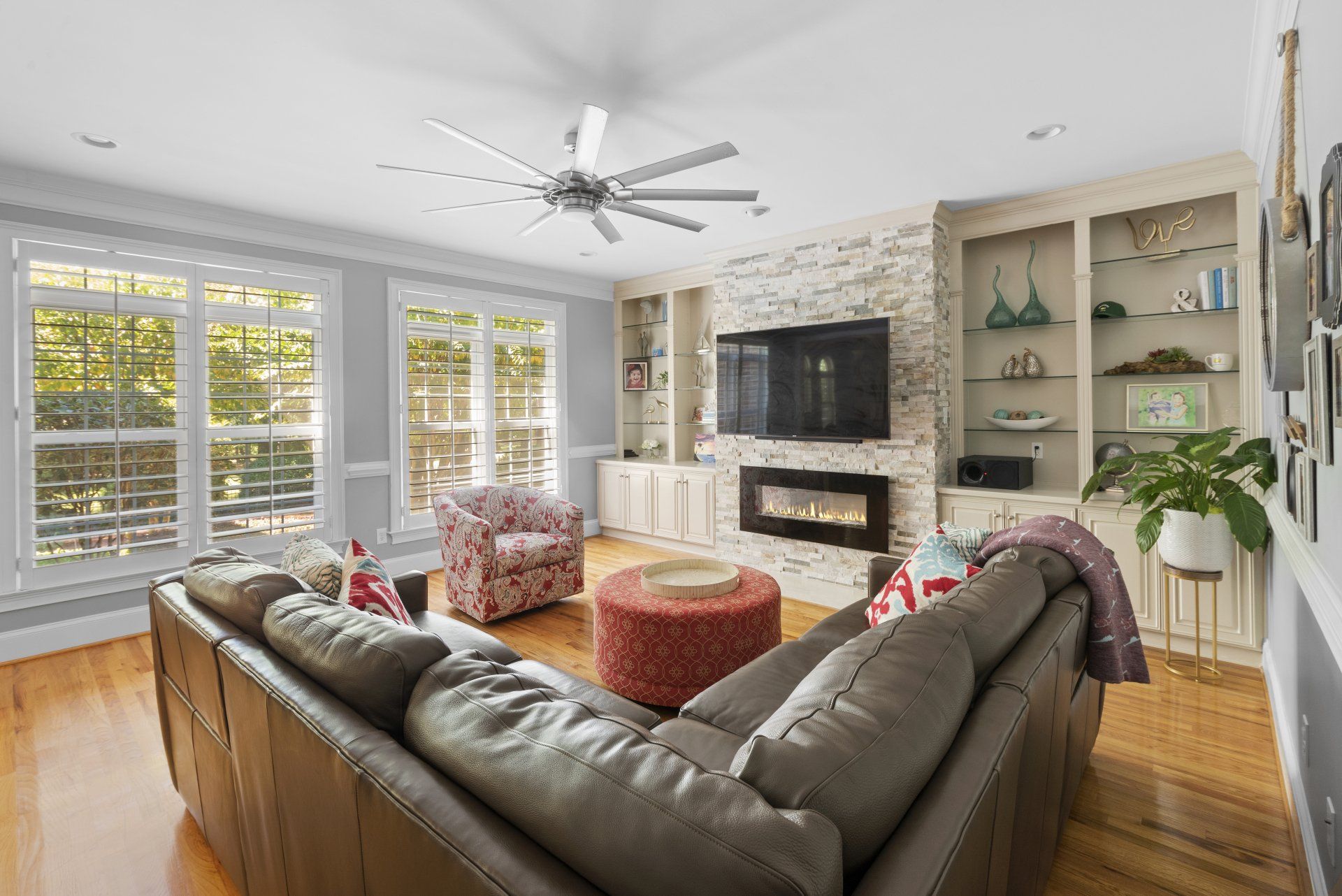 Living room with large sectional sofa, fireplace, built-in shelving, and large windows.