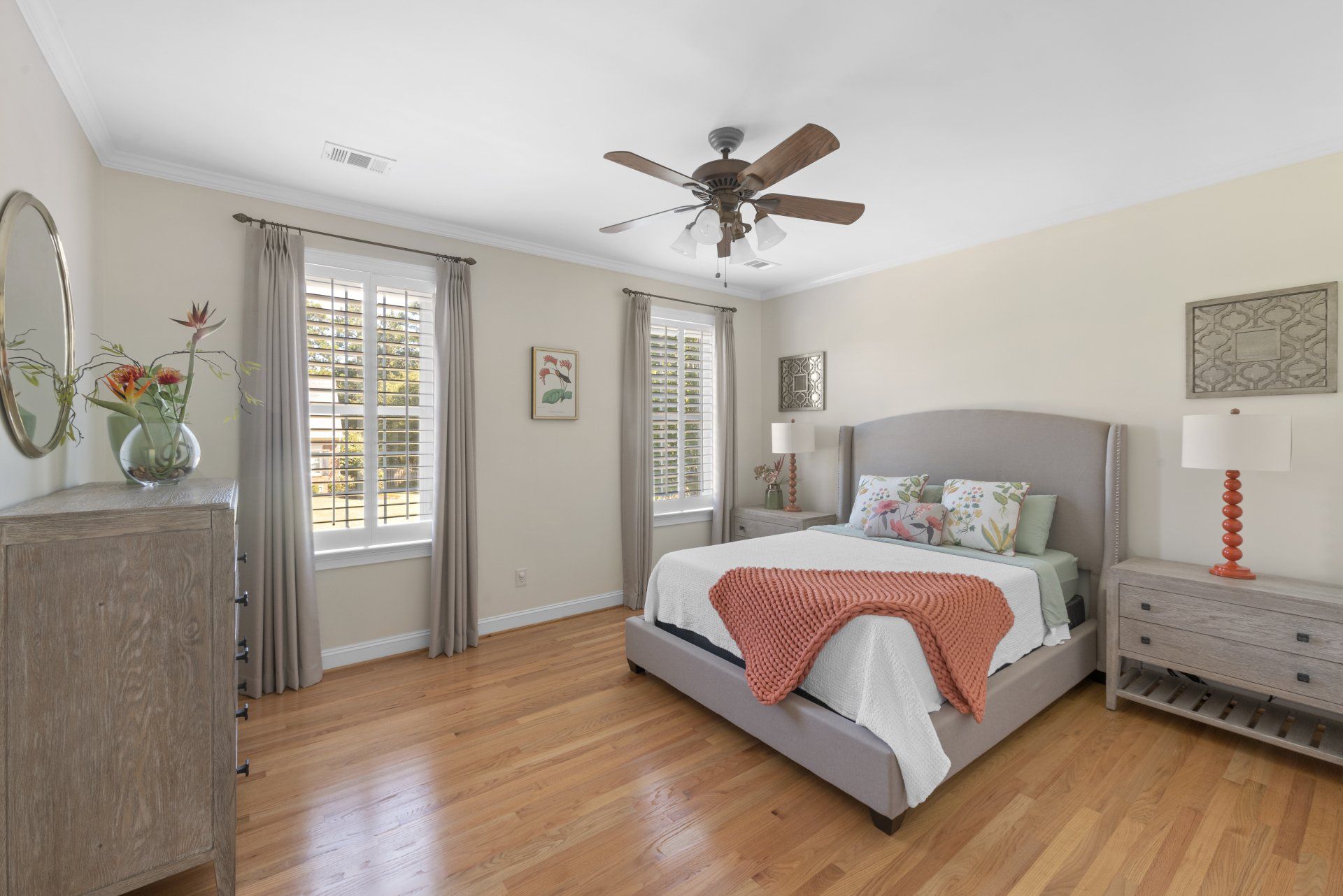 Bedroom with a bed, dresser, windows, hardwood floor, and a ceiling fan.