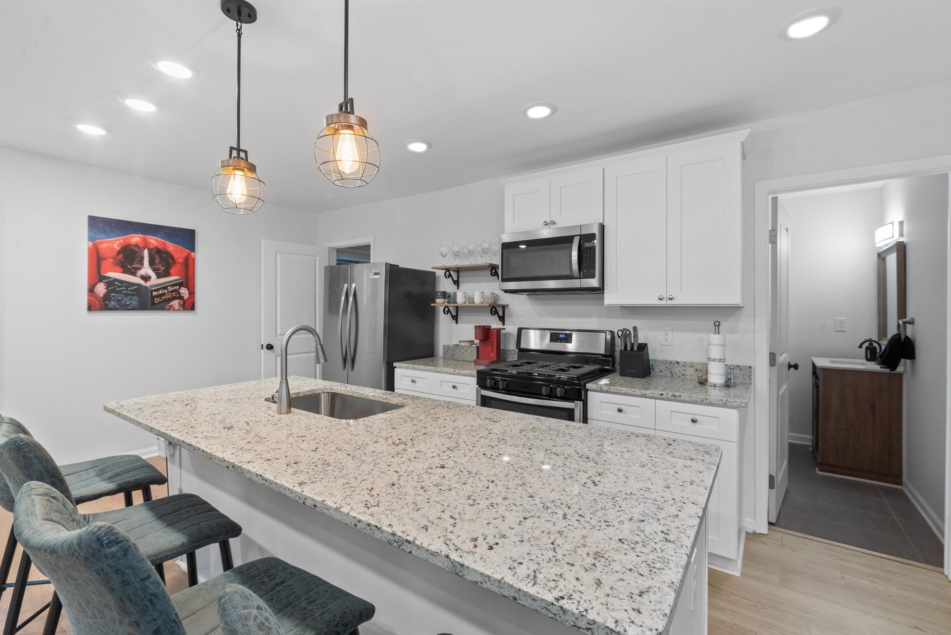 Modern kitchen with island, white cabinets, and granite countertops.