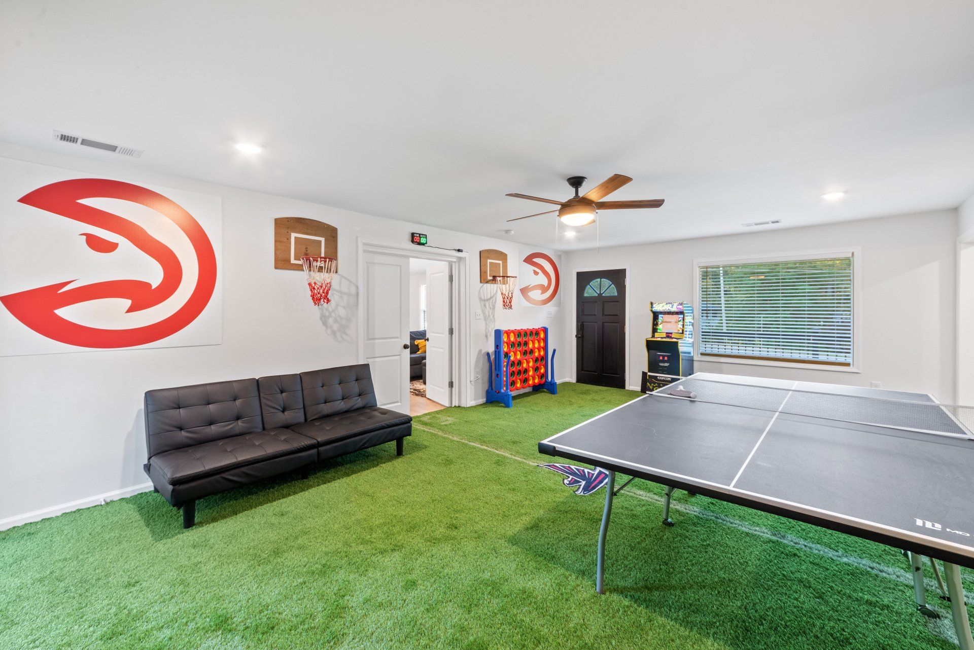 Game room with a basketball hoop, ping pong table, and artificial turf flooring.