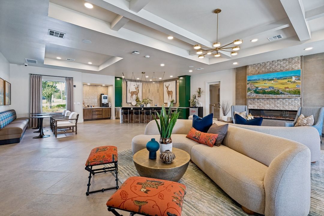 Spacious modern living room with beige sofa, colorful accents, and large landscape artwork
