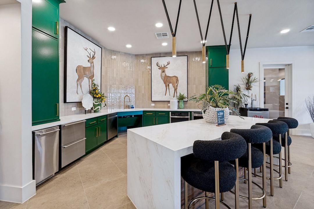 Modern kitchen with white island, green cabinets, bar stools, and deer wall art